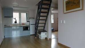 A modern kitchen with a built-in dishwasher, a refrigerator, and a sink. There is a wooden ladder leading to a lofted sleeping area. - Ri-In Mokpo (Mokpo)