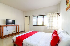 A hotel room with a bed, a TV on a wooden stand, a window with curtains, and a door.