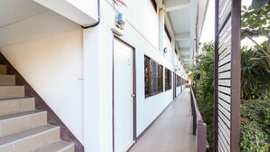 Un couloir avec un escalier sur la gauche, une porte sur la droite et une rambarde le long du chemin.