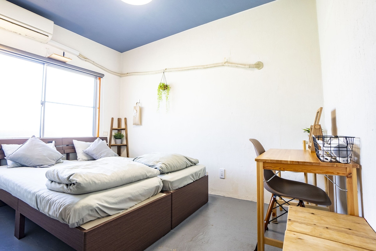 A modern bedroom with a bed, bedside table, and a hanging plant.