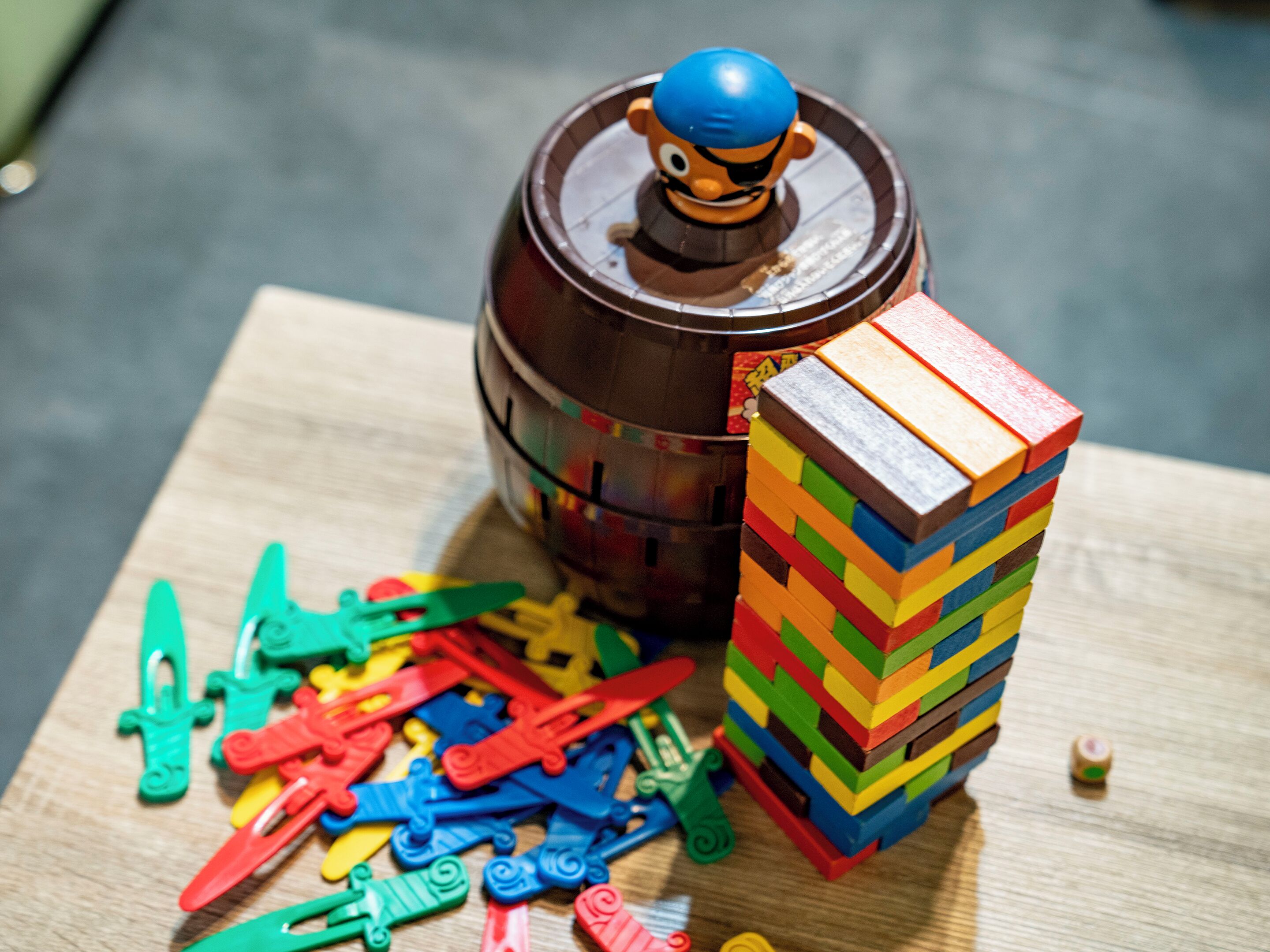 A wooden table with a toy barrel, a stack of colorful building blocks, and scattered toy clips.