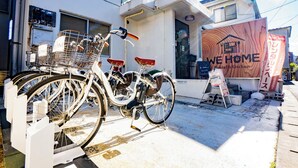 A bicycle parked in front of a building with a sign that reads "WE HOME Hostel & Kitchen".