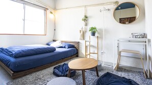 A compact bedroom with a bed, bedside table, chair, and a small desk with a mirror.