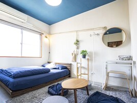 Un dormitorio pequeño con cama, mesita de noche, silla y un escritorio con espejo.