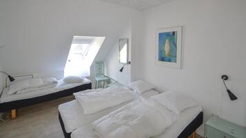 A bedroom with two beds, a skylight, a chair, a painting, and a bedside table.