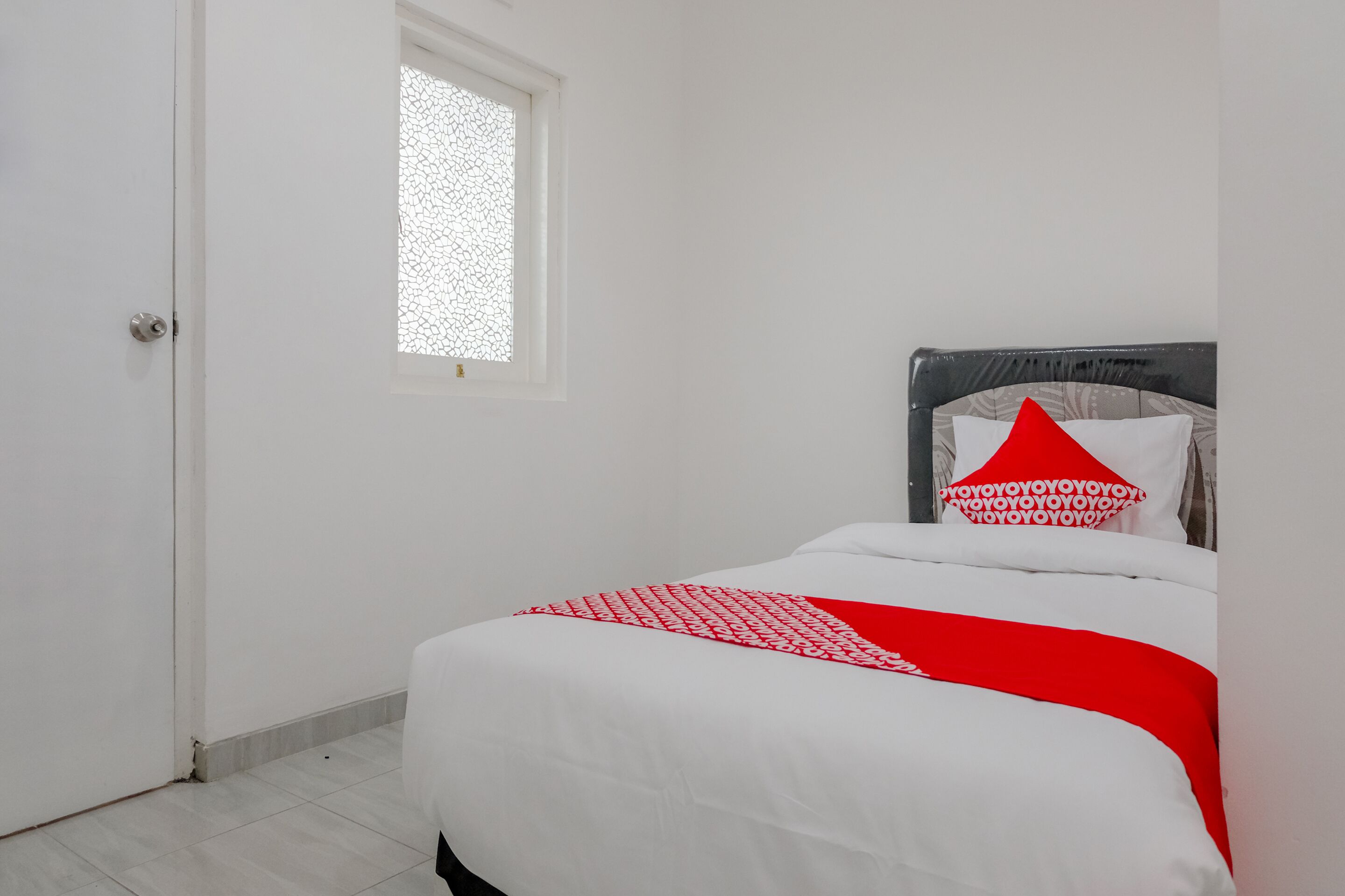Um quarto com uma cama, janela e porta.