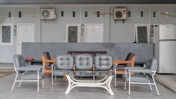 A modern waiting area with a sofa and six chairs, air conditioning units, and a refrigerator.