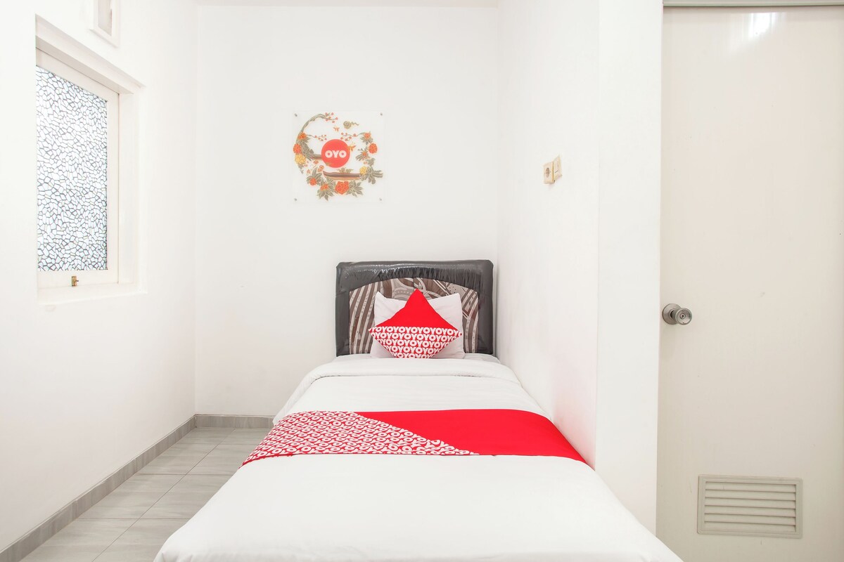 A small, clean room with a bed, a window, and a door.