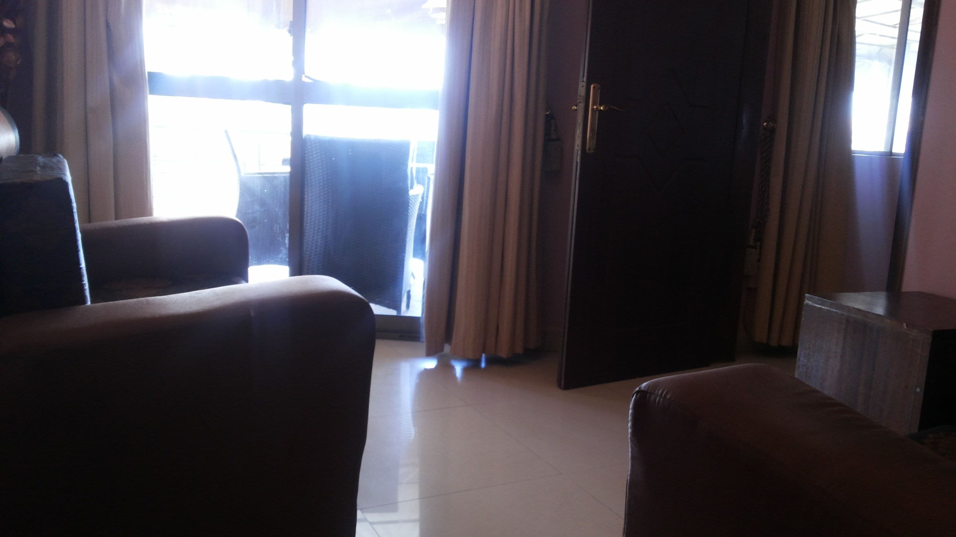 A room with a large window, a door, and two armchairs.