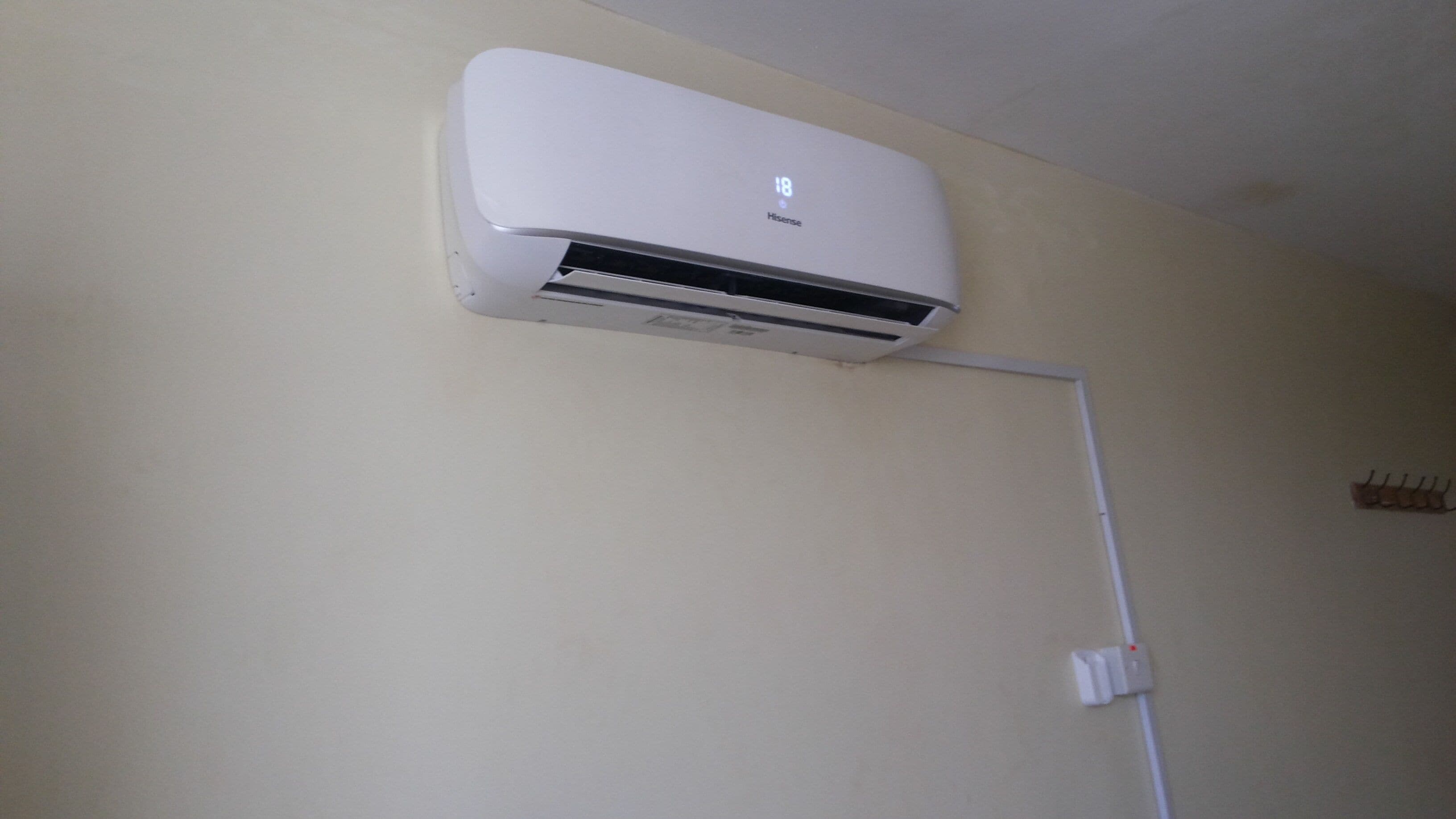A white wall-mounted air conditioning unit with a digital display showing the temperature.