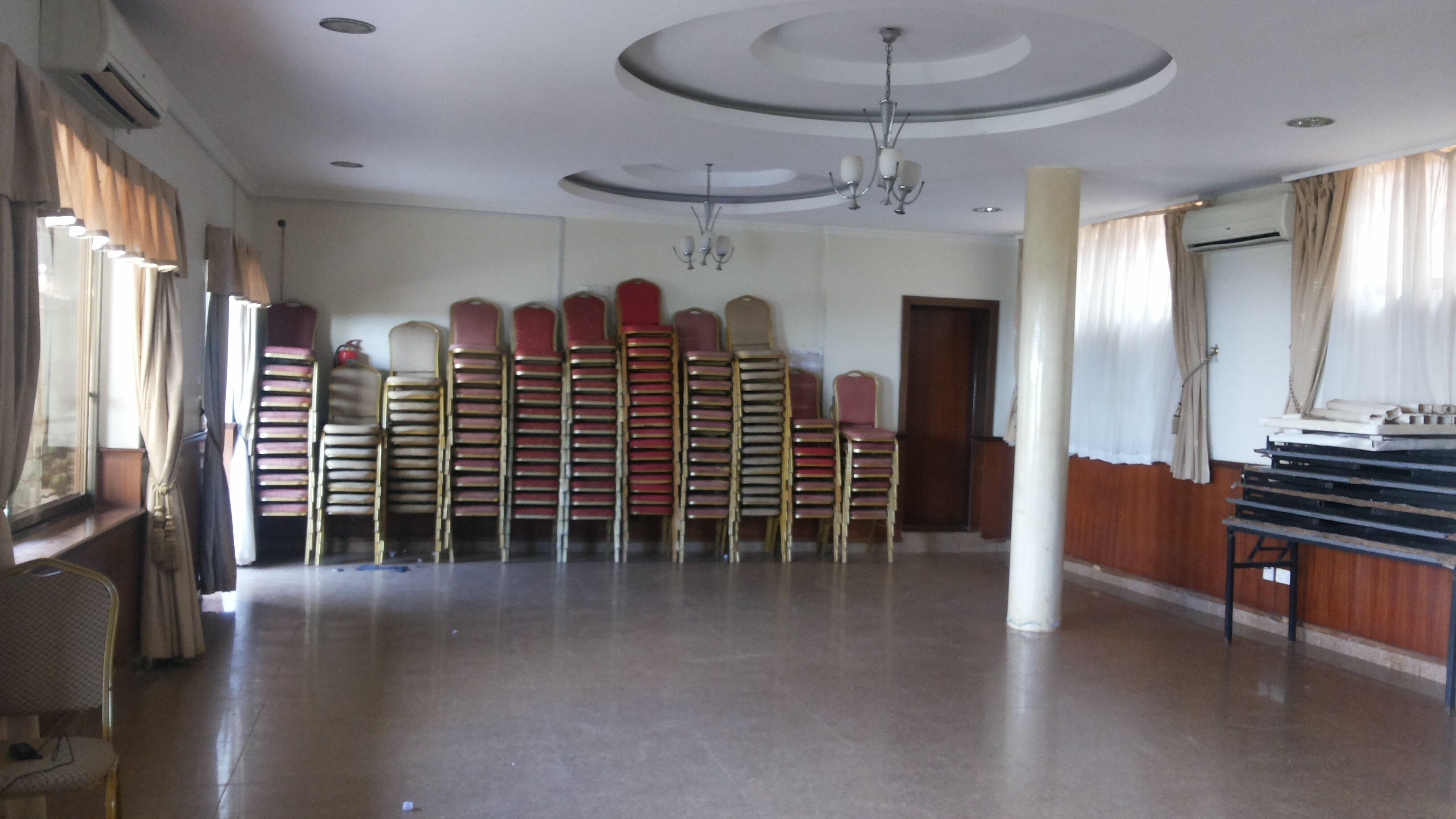 A spacious hall with rows of chairs, a chandelier, and a large pillar.