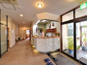 A hotel lobby with a reception desk, a waiting area, and a view of the outdoors through large windows. - Hotel Shibataya (Kurihara)