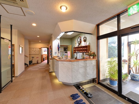 A hotel lobby with a reception desk, a waiting area, and a view of the outdoors through large windows.
