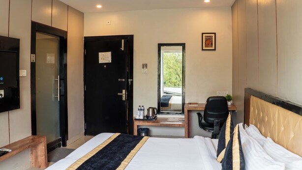 A hotel room with a bed, desk, chair, and a ceiling fan. - Hotel Runway Inn (Pindra)