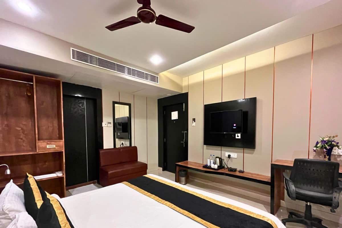 Una habitación de hotel con una cama grande, un escritorio, una silla, un televisor y un armario.