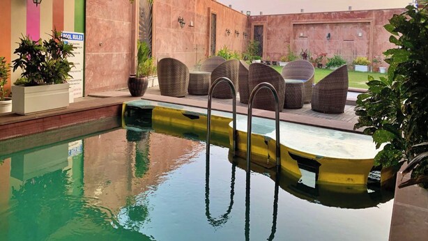 Una piscina interior con techo colorido, sillones de mimbre y plantas en macetas.
