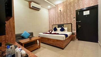 A hotel room with a bed, a desk with a computer, a ceiling fan, and a door.