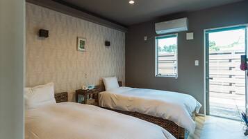 Ett hotellrum med två sängar, ett litet sängbord med en lampa, en luftkonditioneringsanläggning och ett fönster med utsikt över omgivningen.