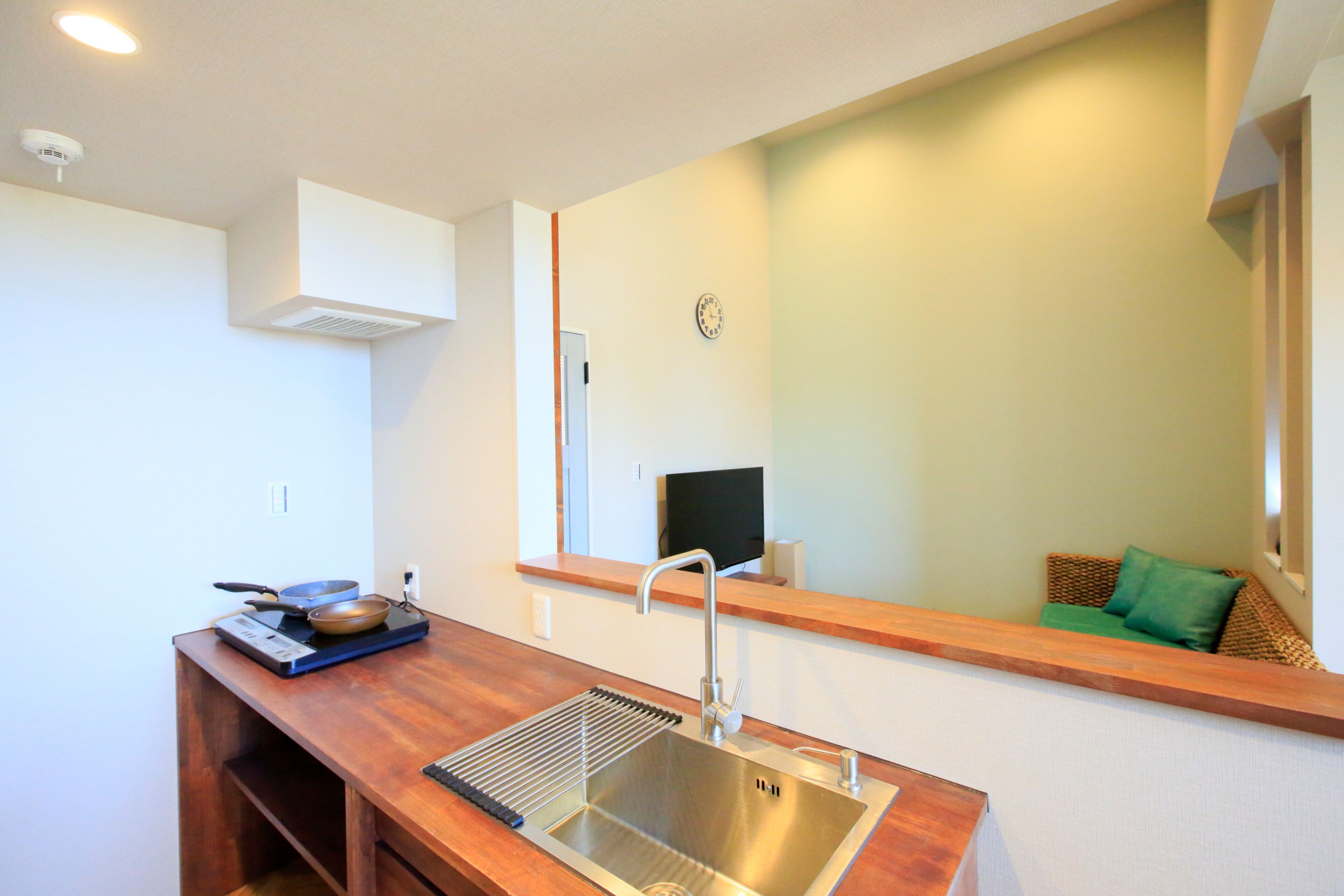 A modern kitchen with a stainless steel sink, wooden countertop, and a built-in range hood.