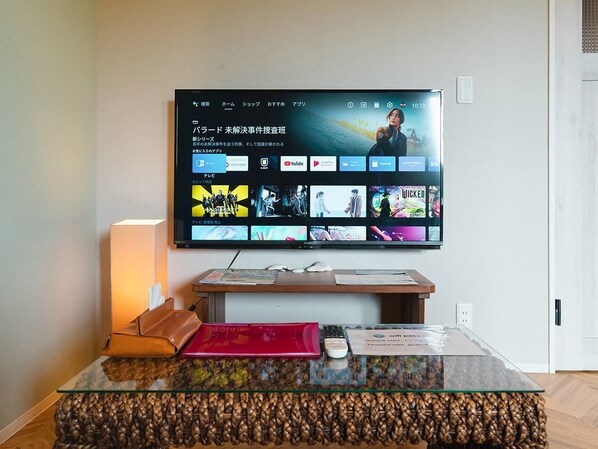 A flat-screen TV mounted on a wall displaying various streaming content. - Alezedvilla Shiraho (Ishigaki)