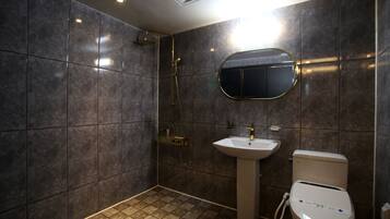 A modern bathroom with dark tiles, a shower, a sink, and a toilet.