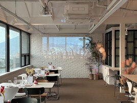 A modern office space with white brick walls, large windows, and a view of the cityscape.