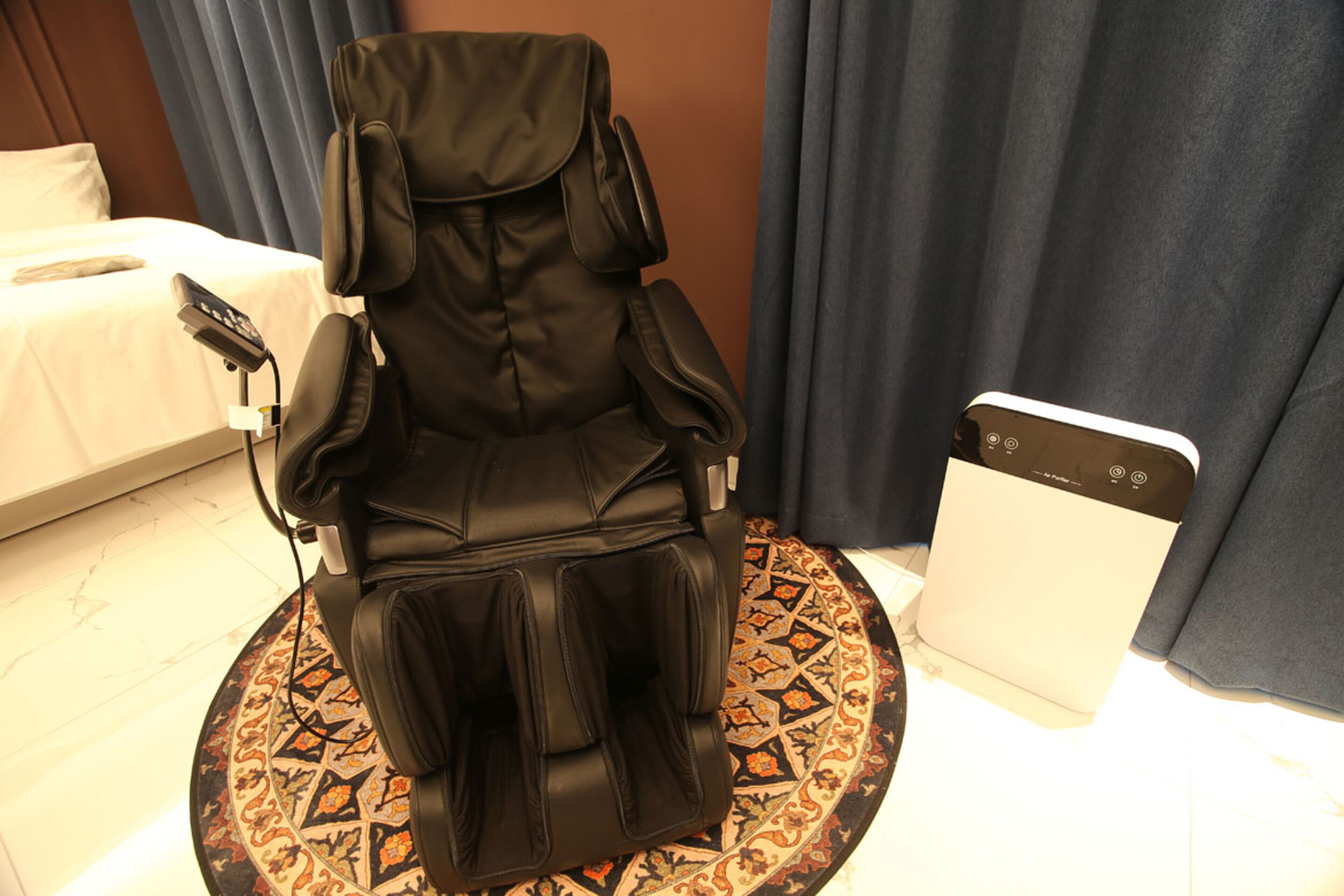 A massage chair in a hotel room with a bed and a control panel.