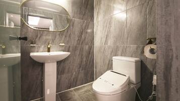 A bathroom with a pedestal sink, a toilet, and a mirror.