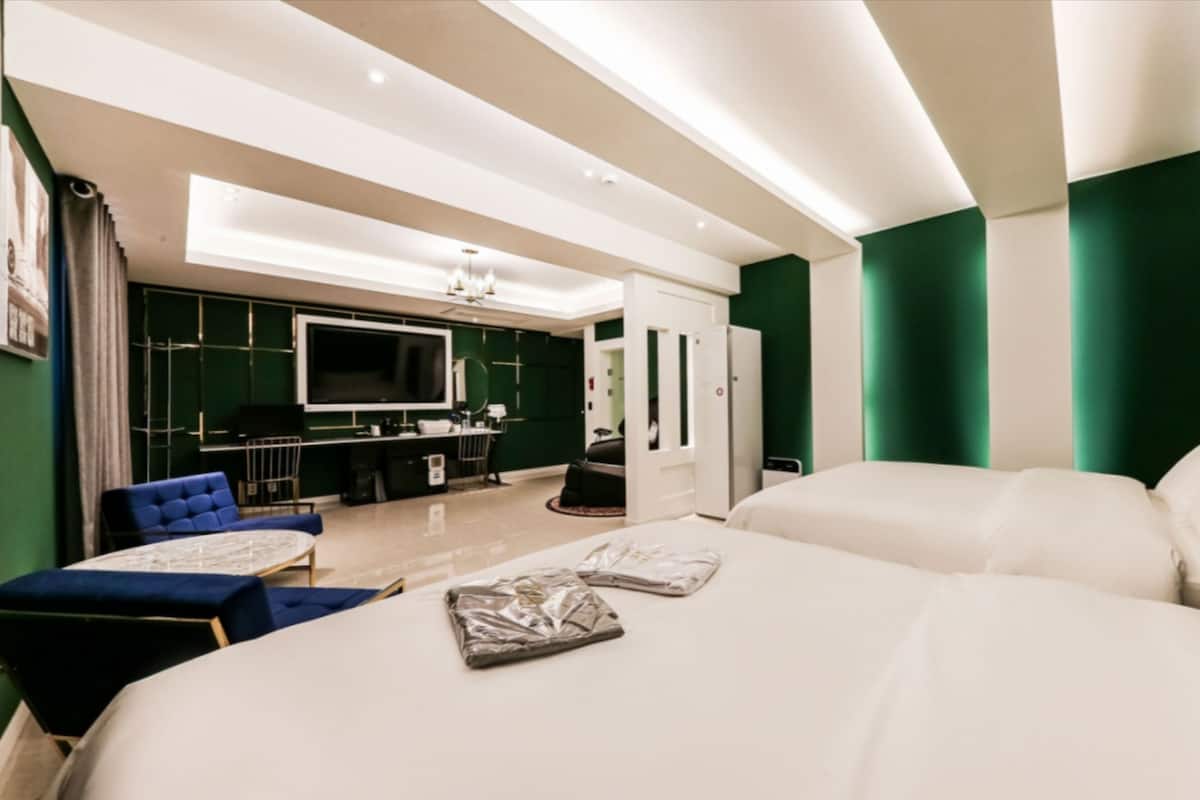 Quarto de hotel moderno com uma cama grande, um sofá, uma mesa, uma TV e um minibar.