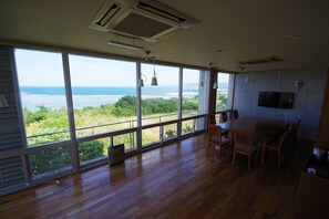 A spacious room with large windows offering a view of the ocean and greenery. - Resort in Villa Yamabare (Ishigaki)