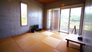 Une pièce avec un sol recouvert de tatamis, un téléviseur posé sur un meuble bas et une table sur laquelle se trouve une boîte de mouchoirs.