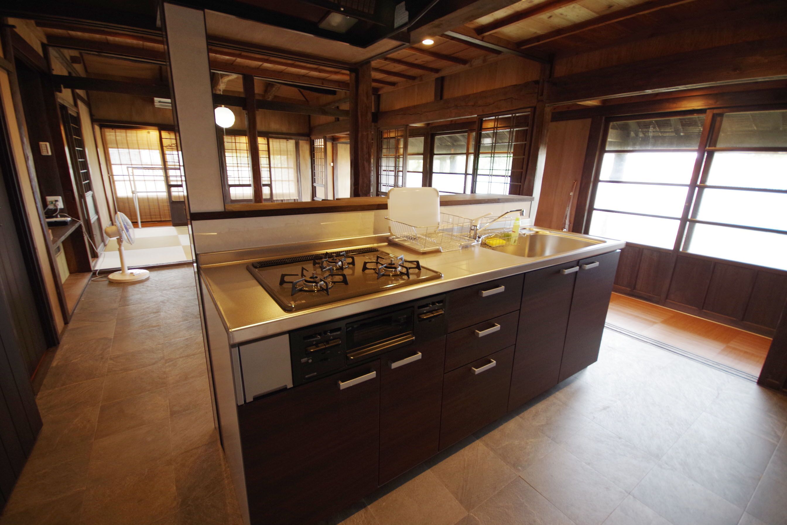A modern kitchen with a central island, built-in appliances, and large windows.
