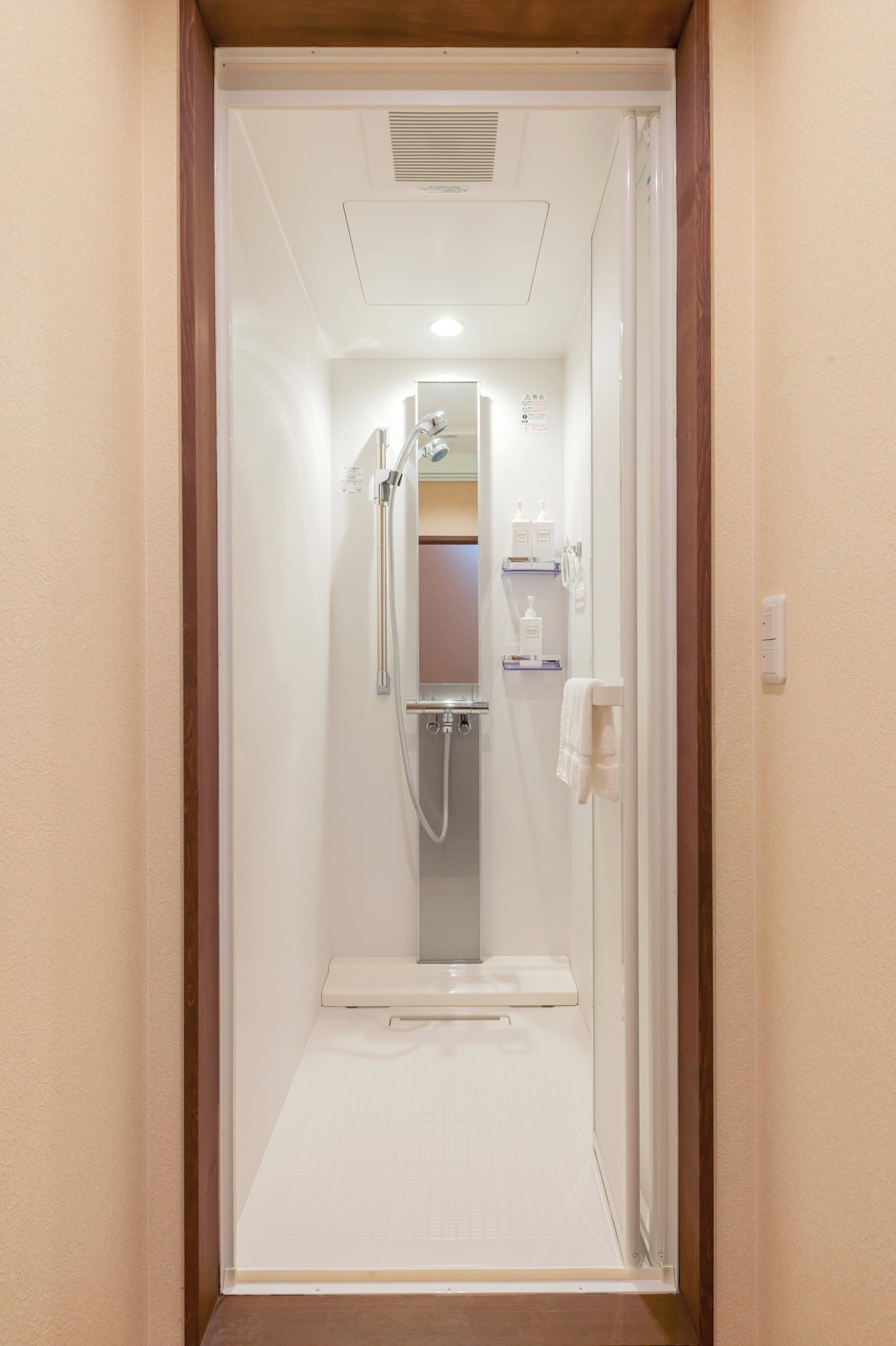 A bathroom with a shower, a mirror, and a towel rack.