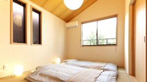 Ein Schlafzimmer mit zwei Betten, einem großen Fenster und einer Klimaanlage.