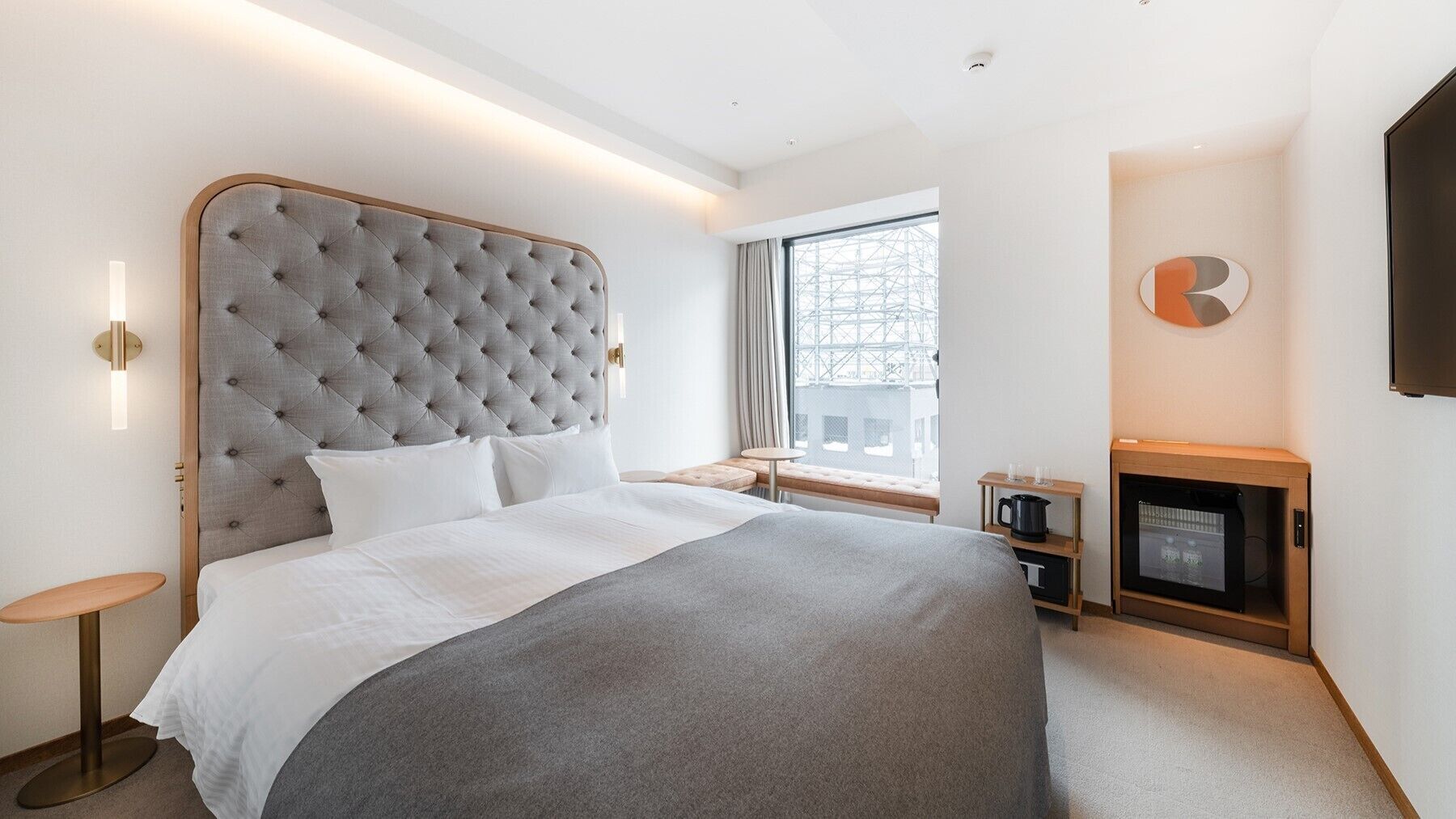 Une chambre d’hôtel moderne dotée d’un grand lit, d’une petite table, d’une cheminée et d’une fenêtre donnant sur la ville.