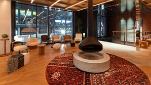 A modern interior with a central fireplace, comfortable seating, and large windows offering views of the outside. - The Knot Sapporo (Sapporo)