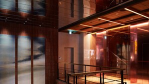 A modern interior with a wooden panel wall, a staircase with metal railings, and a ceiling with exposed beams and lighting. - The Knot Sapporo (Sapporo)