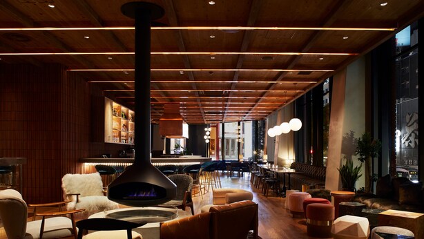 A modern lounge area with a central fireplace, seating arrangements, and a bar in the background. - The Knot Sapporo (Sapporo)