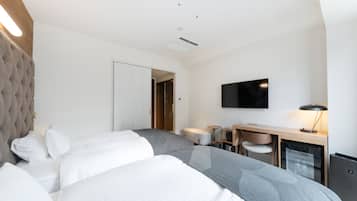 Una habitación de hotel moderna con una cama grande, un escritorio con silla, un televisor de pantalla plana y un minibar.