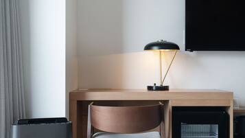 A compact workspace with a desk, chair, lamp, and a mini-fridge.