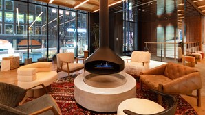A modern lounge area with a central fireplace, comfortable seating, and large windows offering a view of the cityscape. - The Knot Sapporo (Sapporo)