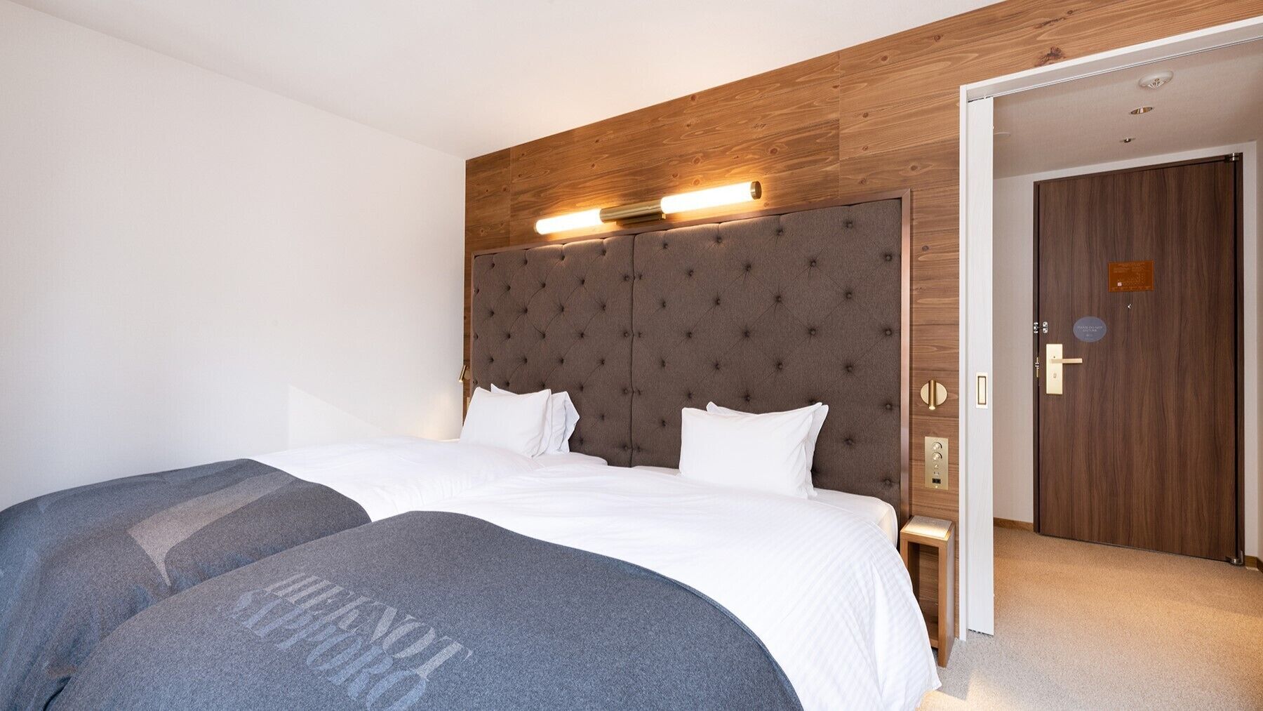 Une chambre d’hôtel avec un grand lit, une tête de lit en bois et une porte dotée d’une serrure.