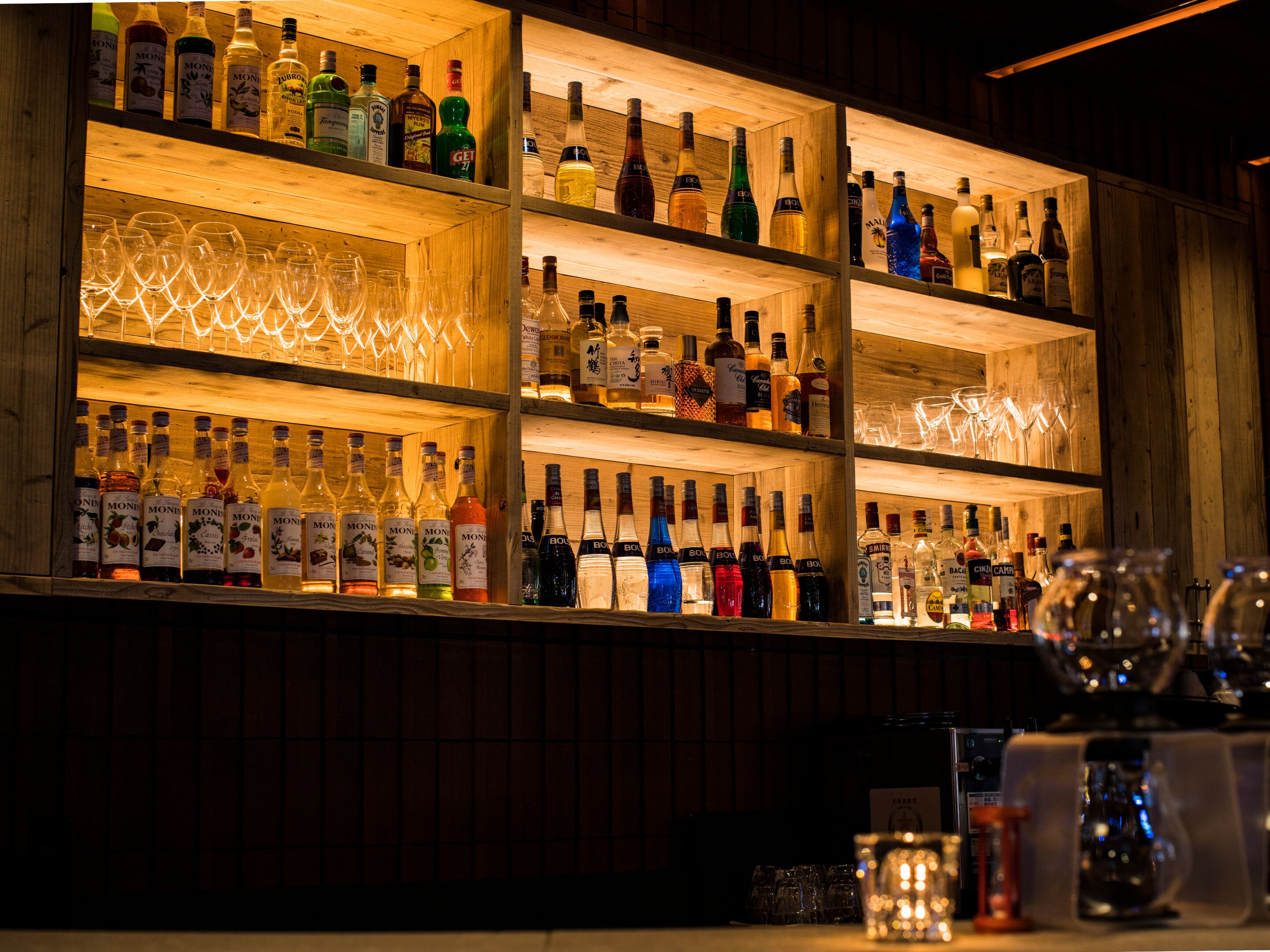A bar with multiple shelves of liquor bottles and glasses.
