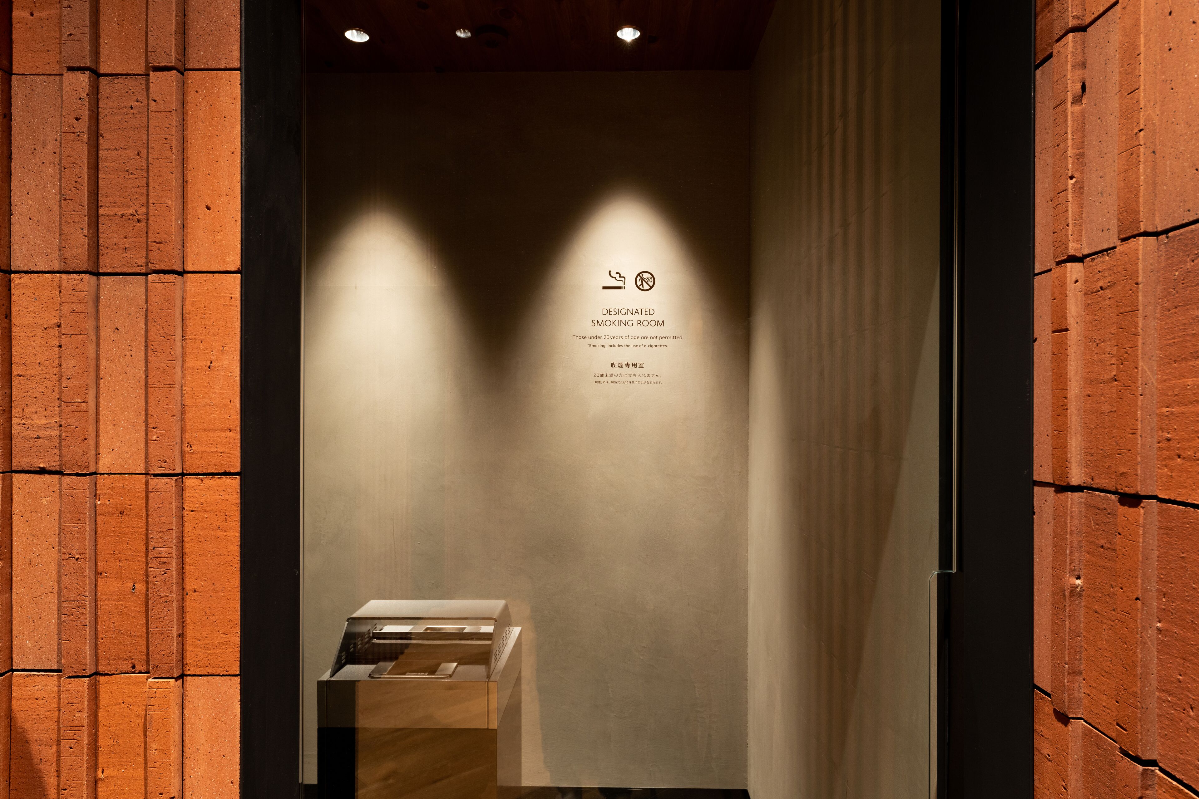 A designated smoking room with a sign, a wooden counter, and a wall with a brick pattern.