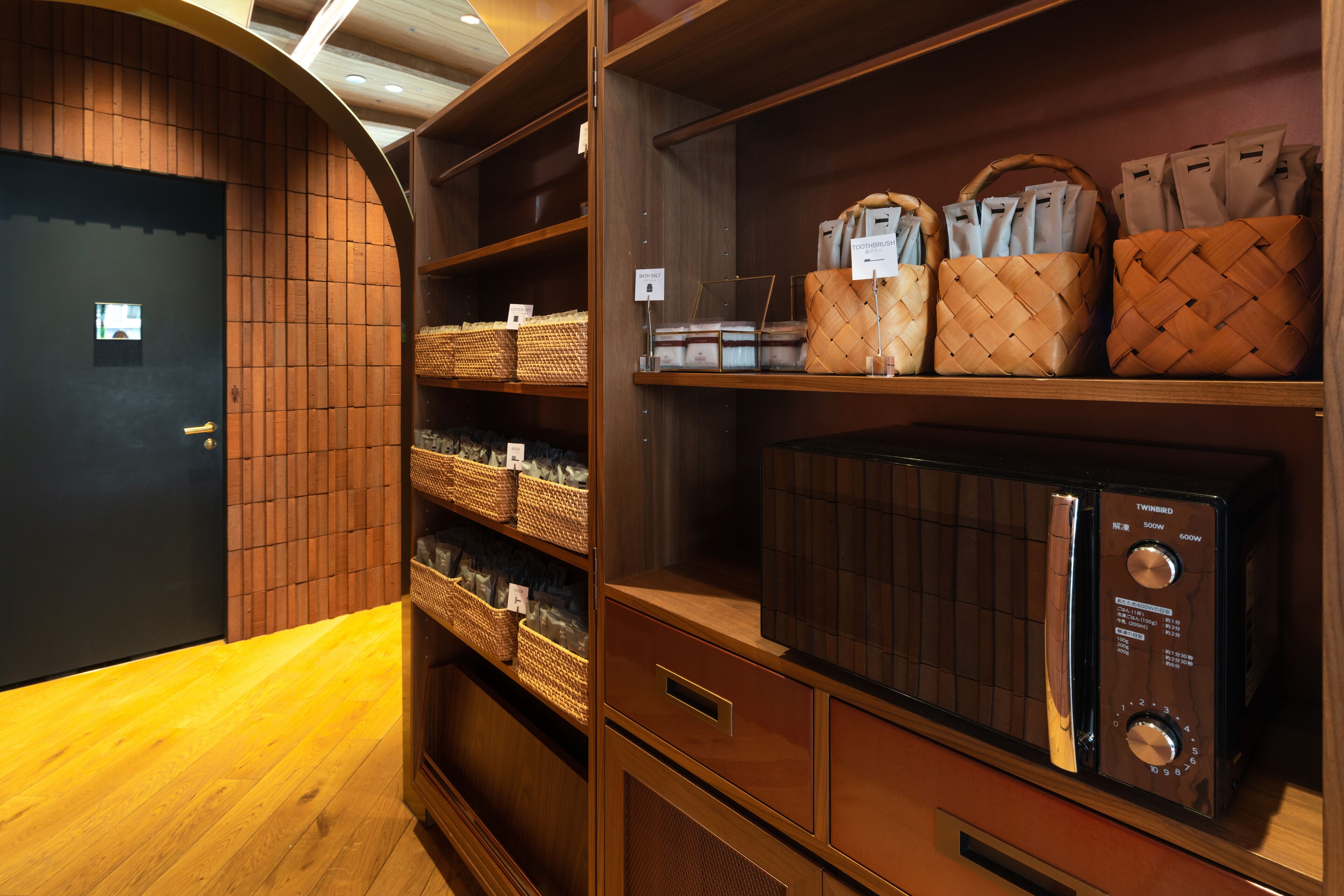 A wooden interior with shelves holding baskets and a microwave.