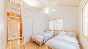 Ein Zimmer mit zwei Betten, einer Leiter, einem Fenster und einer Deckenleuchte.