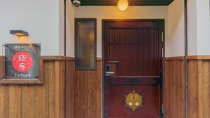 Una porta in legno dal design tradizionale, una targa con caratteri giapponesi e un piccolo finestrino sopra la porta.
