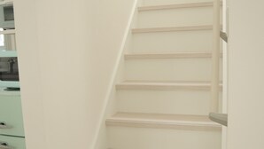 Una escalera con barandilla y pared de color claro.