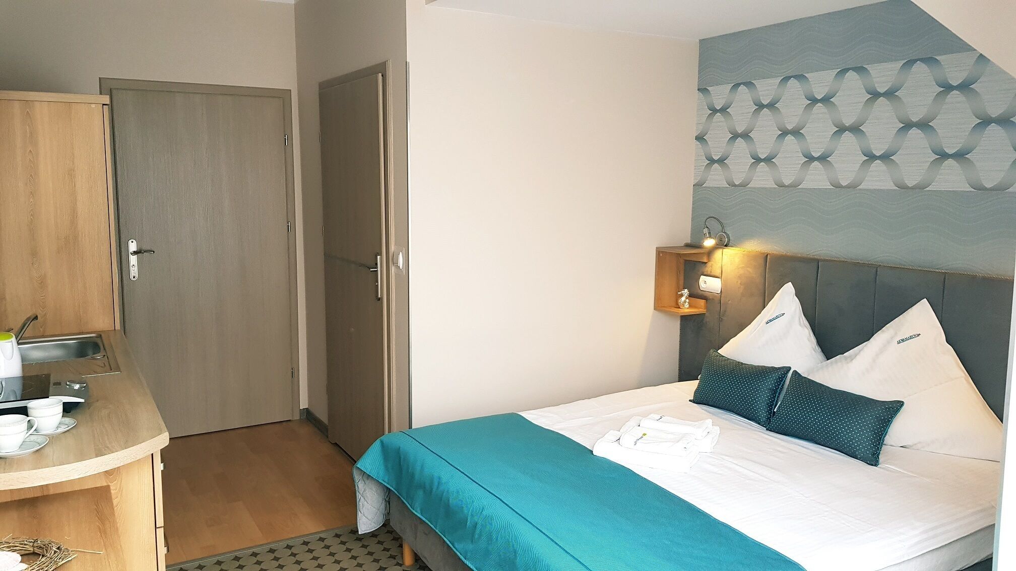 Una habitación de hotel con una cama, un escritorio con silla, una mesita pequeña y un armario.
