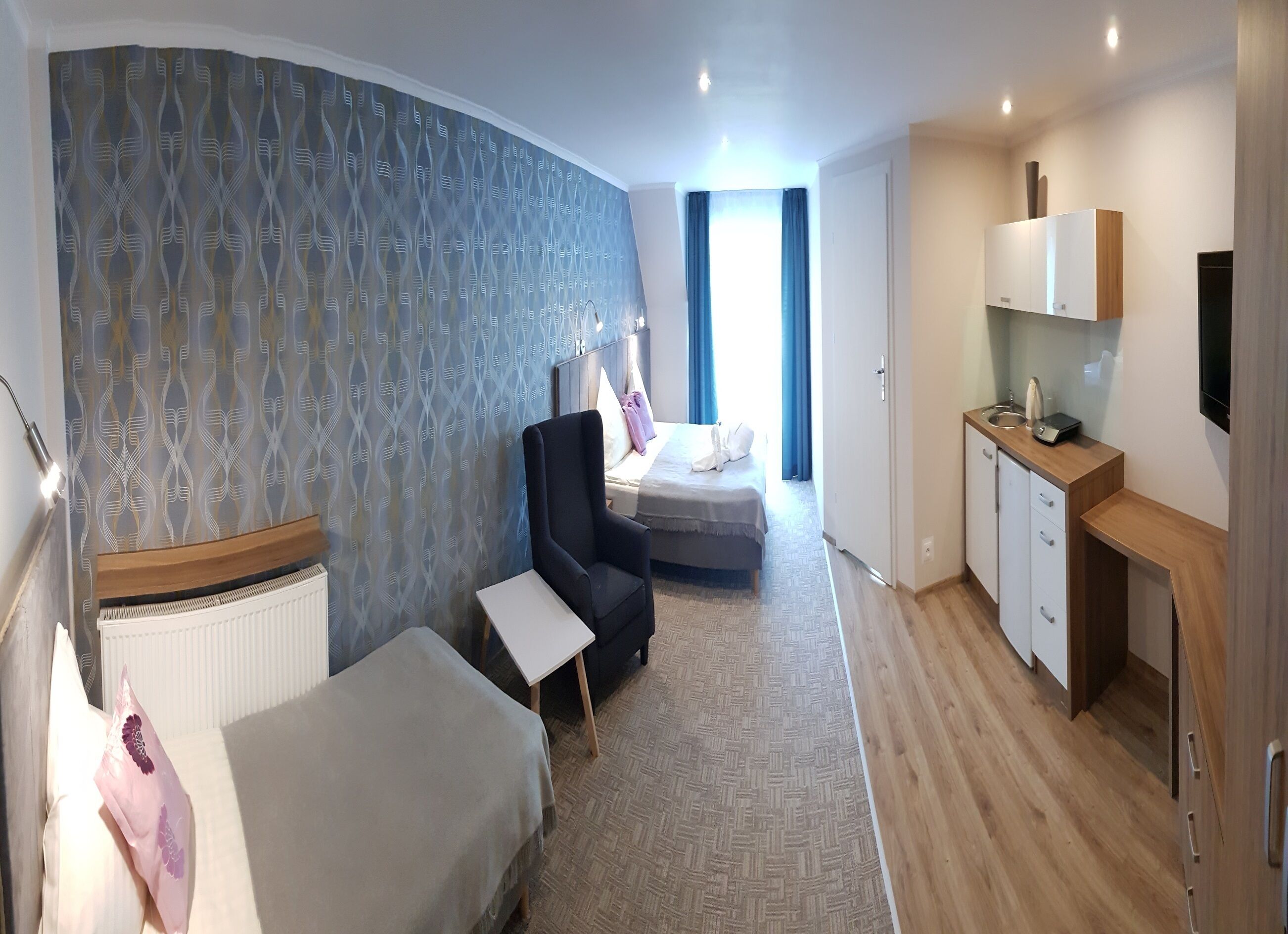 Camera d'albergo con un letto, una scrivania, una sedia, un tavolino, un armadio, una televisione e un bagno con doccia e toilette.